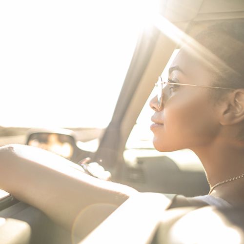 Business woman sitting in front of car